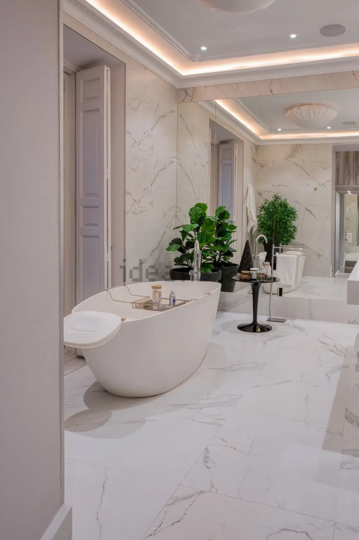 Baño principal de mármol con bañera exenta y plantas