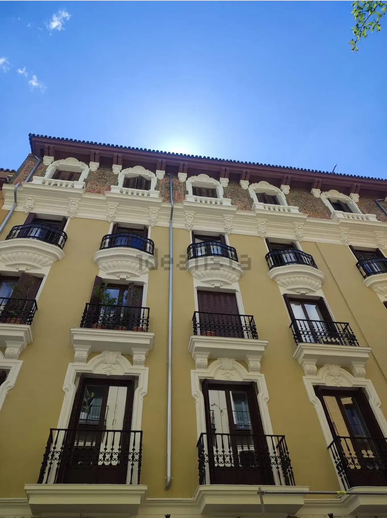 Detalle de la fachada histórica amarilla con balcones ornamentados