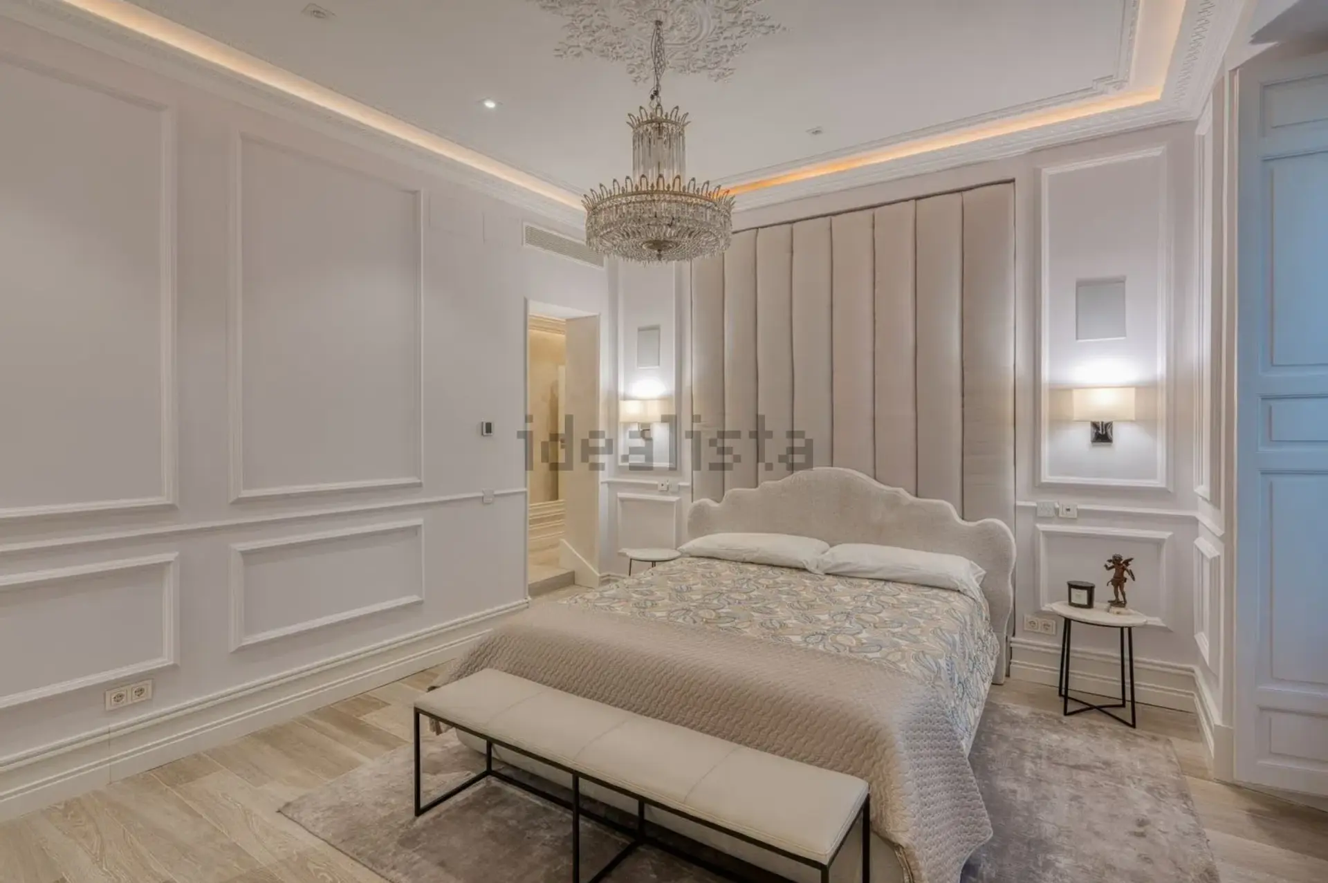 Dormitorio principal con paredes molduradas y balcón