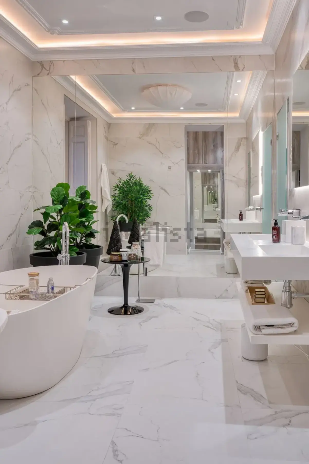 Baño principal de mármol claro con bañera y lavabo doble