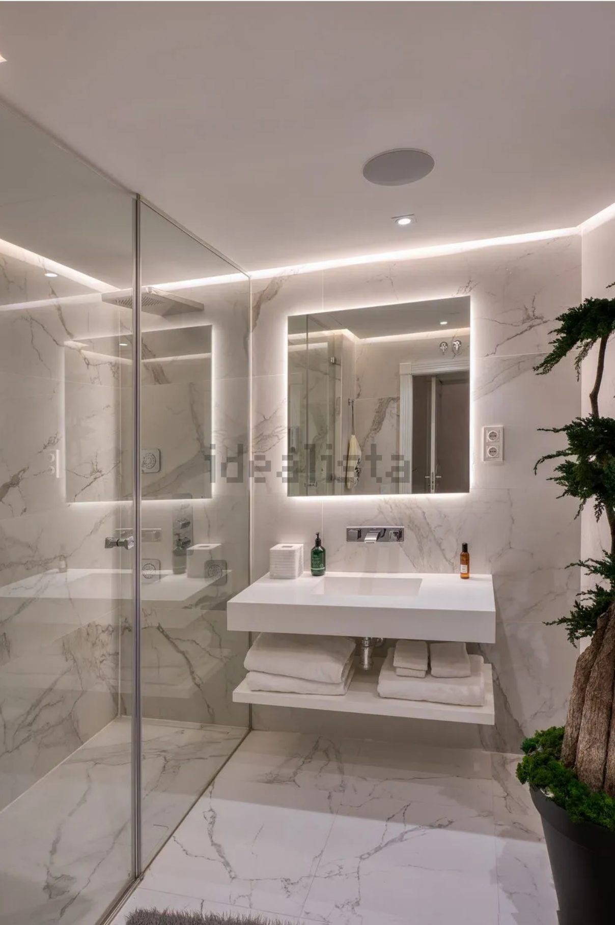 Tercer baño de mármol con lavabo retroiluminado y ducha acristalada